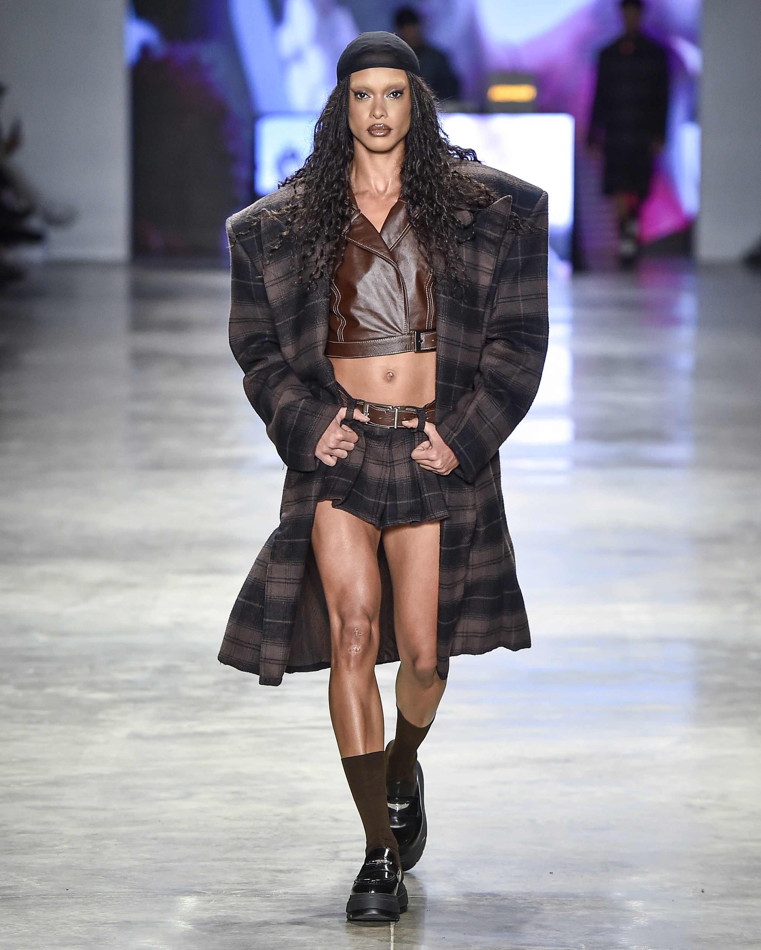 Modelo desfilando com conjunto listrado de casaco e saia