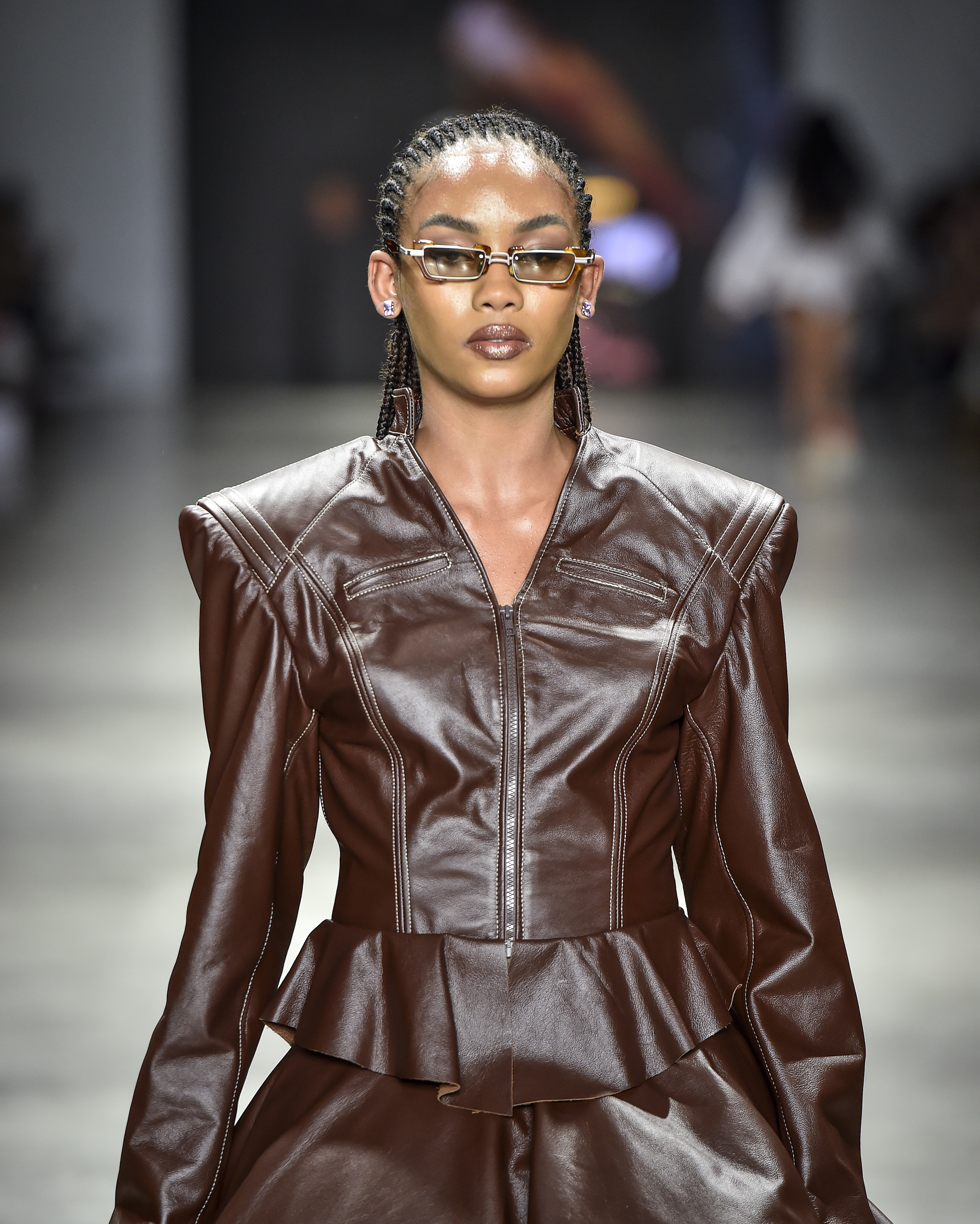 Modelo desfilando para a marca Dendezeiro com uma jaqueta de couro