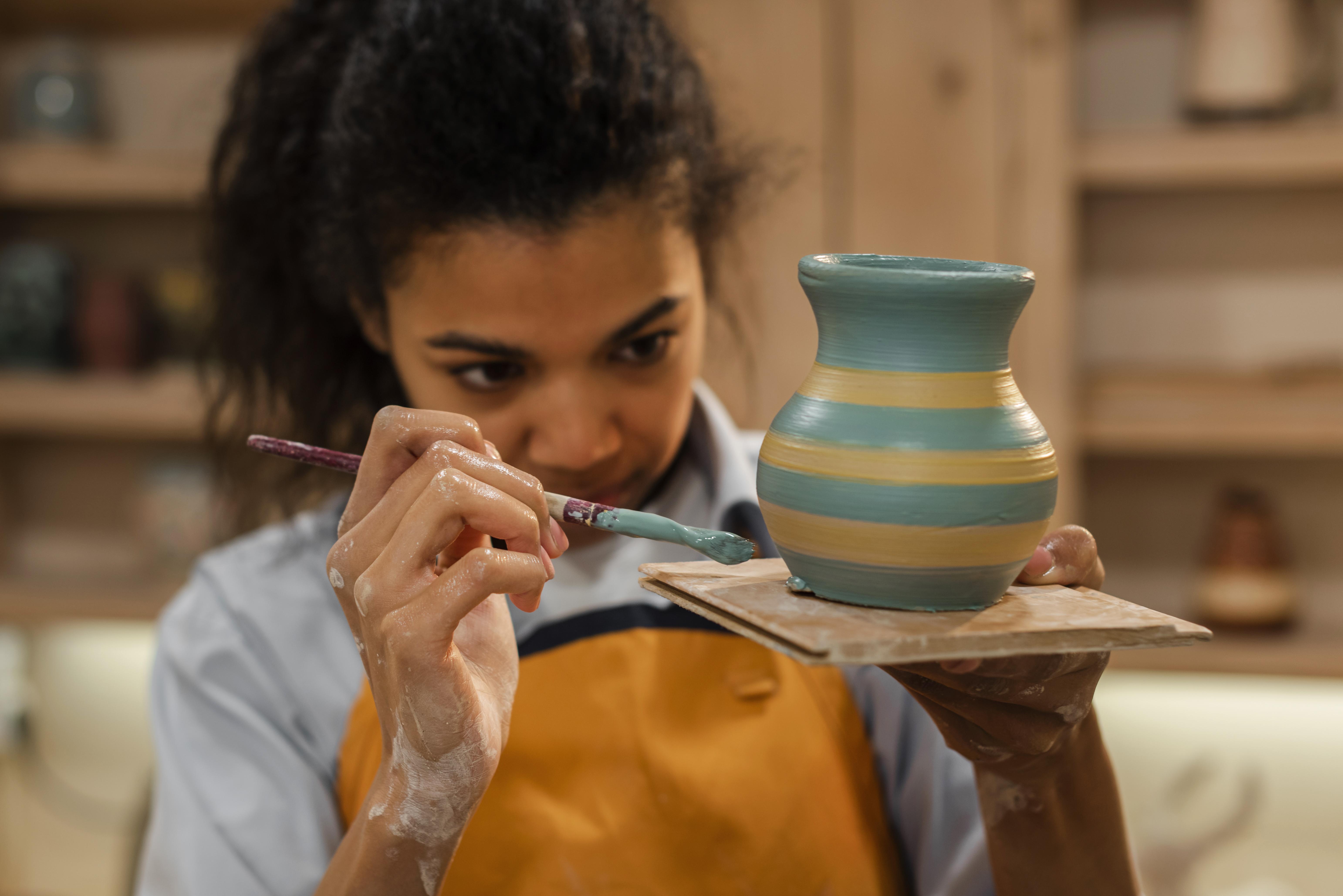 Foto de uma menina jovem pintando uma cerâmica.