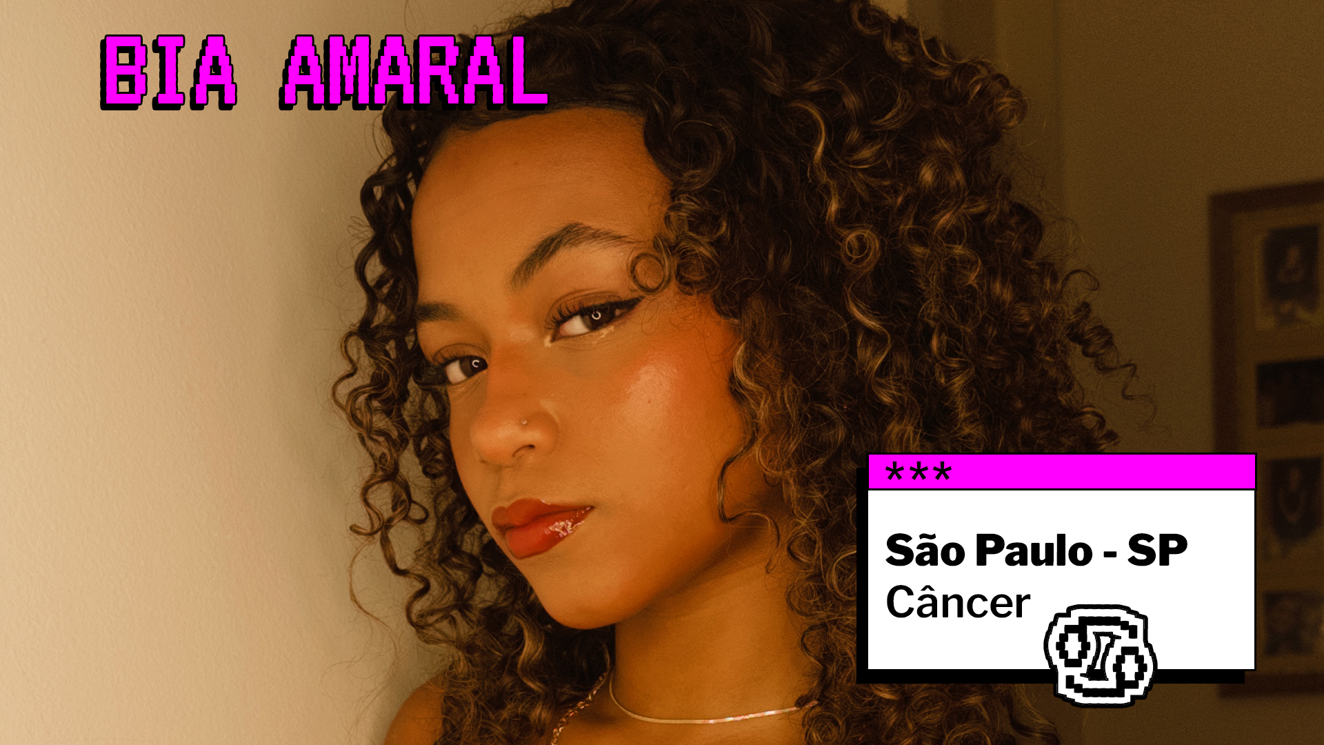 Retrato de uma jovem com cabelos cacheados e maquiagem leve, olhando para a câmera. No topo da imagem, aparece o nome “Bia Amaral” em destaque. À direita, há um quadro com as informações “São Paulo - SP” e “Câncer”, acompanhado de um ícone do signo.