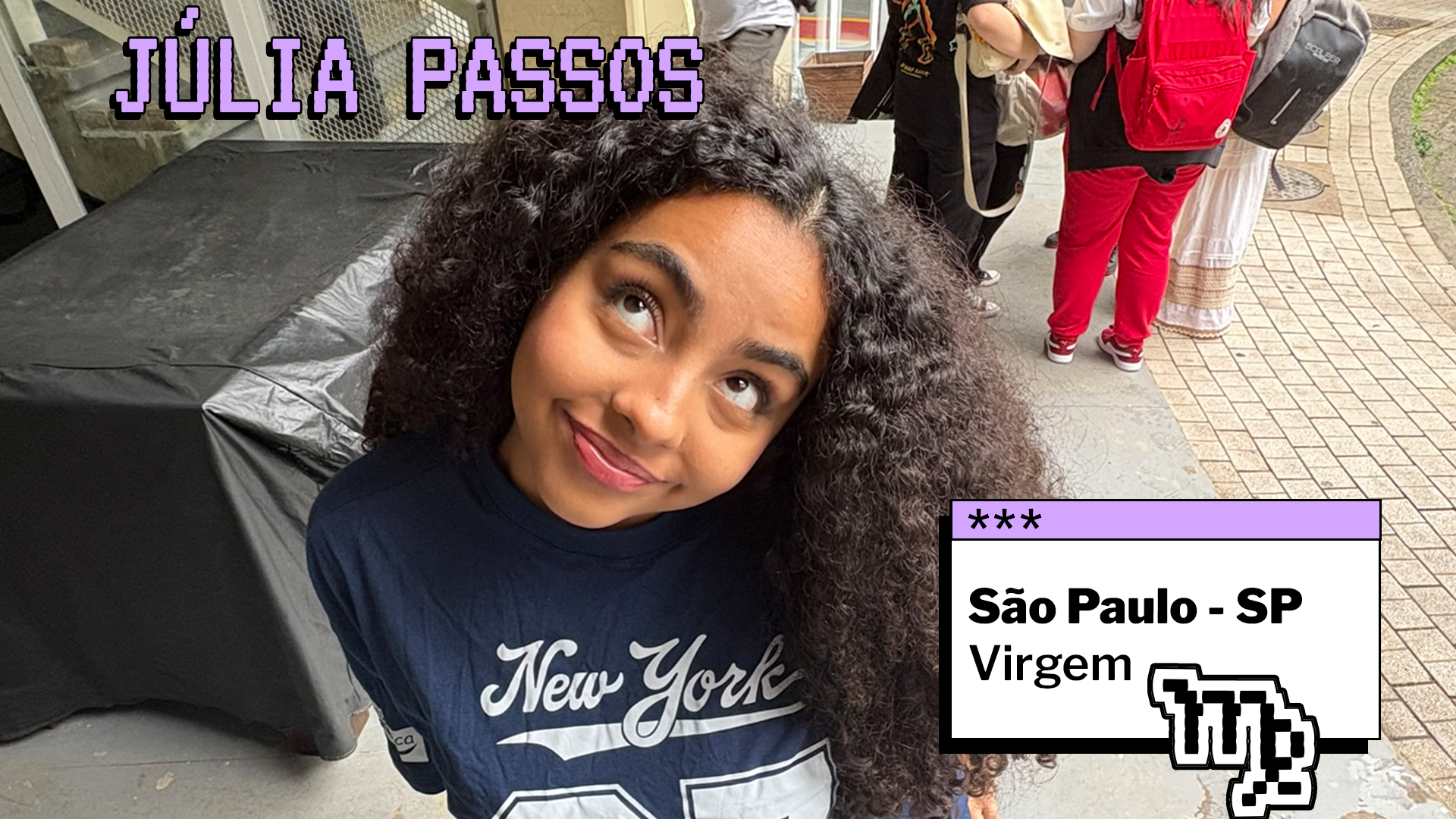 Pessoa jovem com cabelos longos e cacheados posa ao ar livre, inclinando a cabeça e olhando para cima com expressão leve e sorridente. Ela veste uma camiseta escura com a palavra “New York”. Ao fundo, há outras pessoas e uma calçada. No topo da imagem está escrito “JÚLIA PASSOS”. No canto inferior direito, um quadro indica “São Paulo - SP” e o signo “Virgem”.