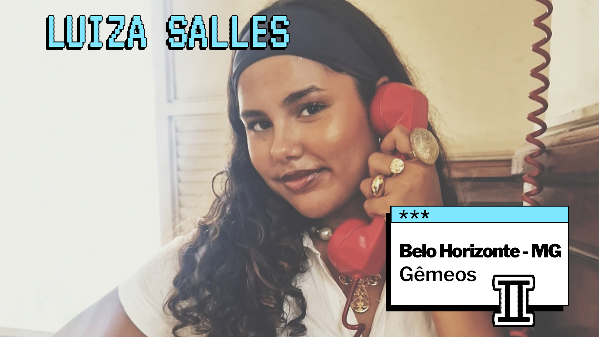 Pessoa jovem com cabelos longos e ondulados posa sorrindo levemente enquanto segura um telefone retrô vermelho junto ao ouvido. Ela usa acessórios dourados, como anéis e colar, e uma blusa clara. No topo da imagem está escrito “LUIZA SALLES”. No canto inferior direito, um quadro indica “Belo Horizonte - MG” e o signo “Gêmeos”.