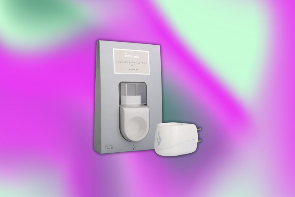 Embalagem cinza vertical de aromatizador elétrico Veo Aroma Standard, com o aparelho branco visível, e um plugue branco separado ao lado, sobre fundo degradê roxo e verde
