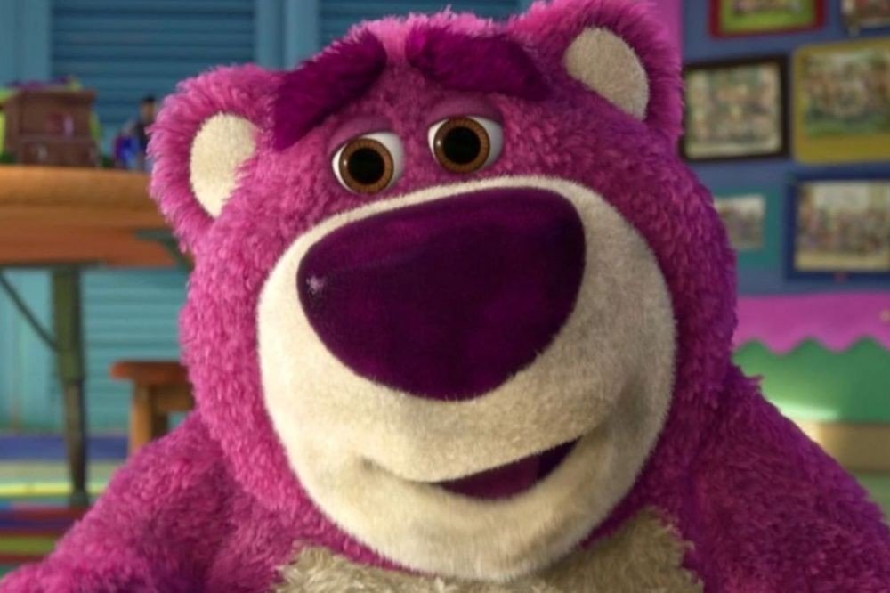 Urso de pelúcia Lotso, rosa e branco, com nariz roxo e sobrancelhas franzidas, olhando para frente com expressão séria