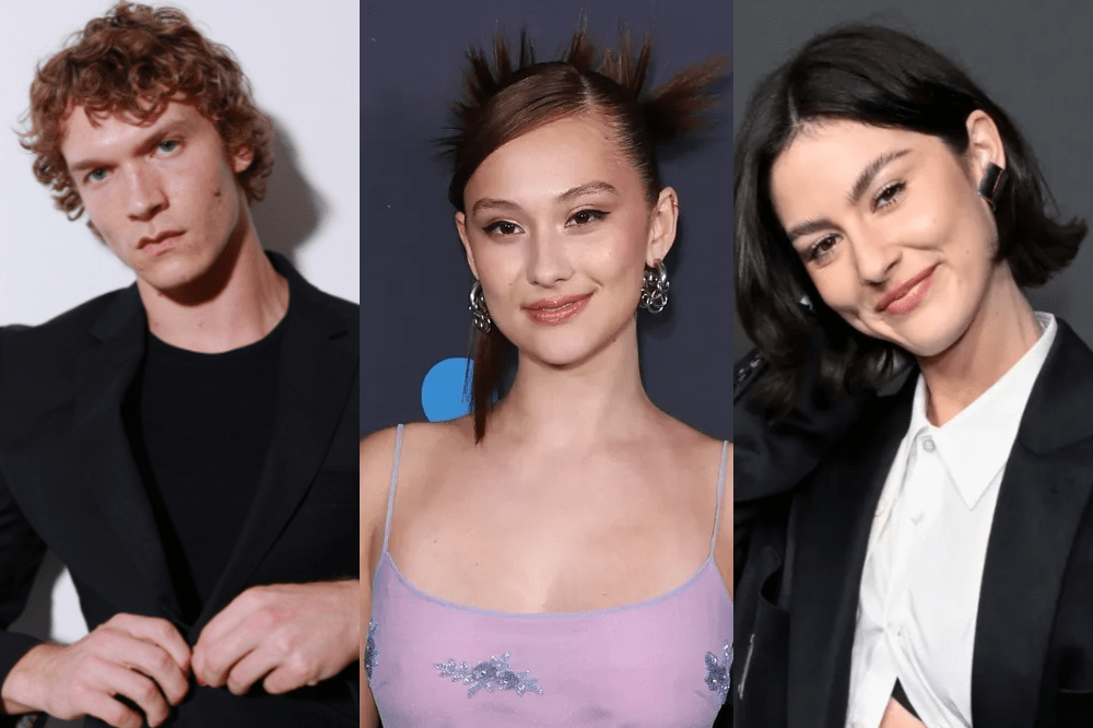 Três pessoas em close-up: um homem ruivo de blazer preto abotoando a jaqueta, uma mulher asiática sorrindo com coque espetado e vestido lilás, e uma mulher de cabelo preto curto sorrindo com blazer preto e camisa branca