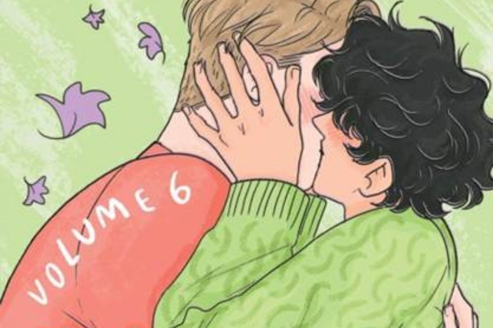 Dois jovens se beijando, um com cabelo loiro e camisa vermelha com VOLUME 6 escrito, o outro com cabelo escuro e suéter verde, com folhas roxas flutuando ao redor