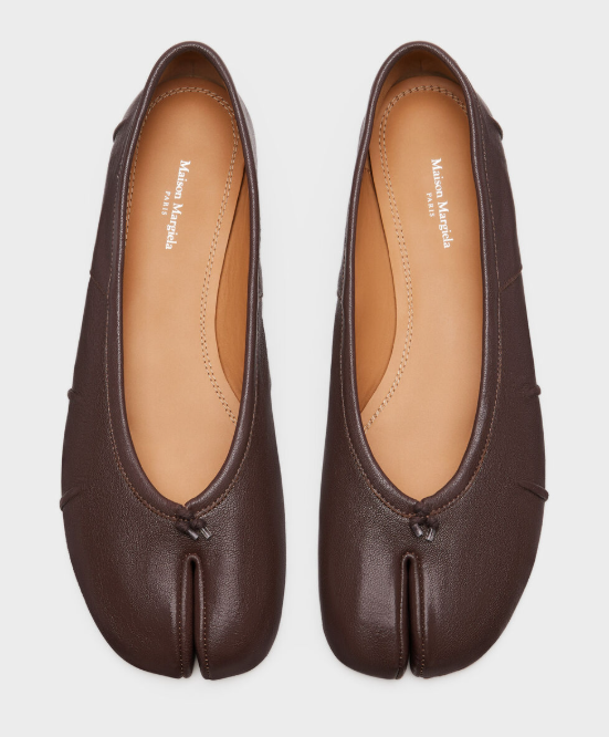 Par de sapatilhas marrons de couro com bico dividido e um pequeno laço na frente, sobre fundo branco. A palmilha bege exibe o logo Maison Margiela Paris